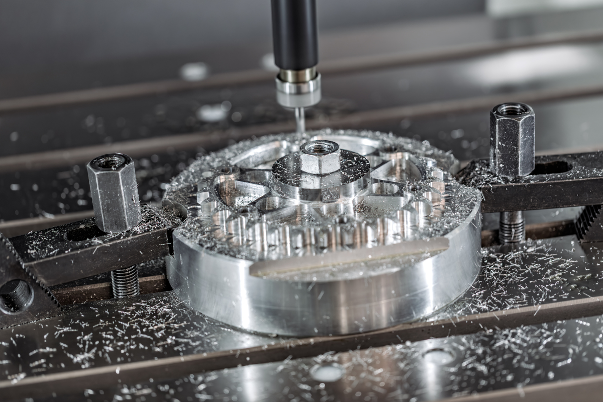 CNC milling an aluminum component secured with clamps, with metal shavings surrounding the workpiece.